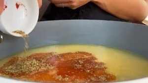 Pouring spices into a pan with broth, perfect for enhancing flavor in cooking recipes.