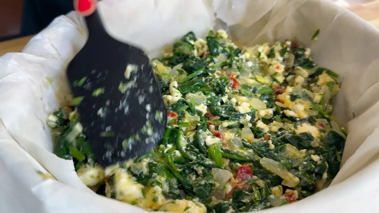 Mixing spinach and feta filling for a savory pie.