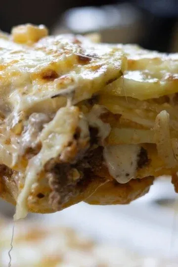 Close-up of cheesy lasagna slice with layers of pasta, meat, and rich creamy sauce. Perfect comfort food.