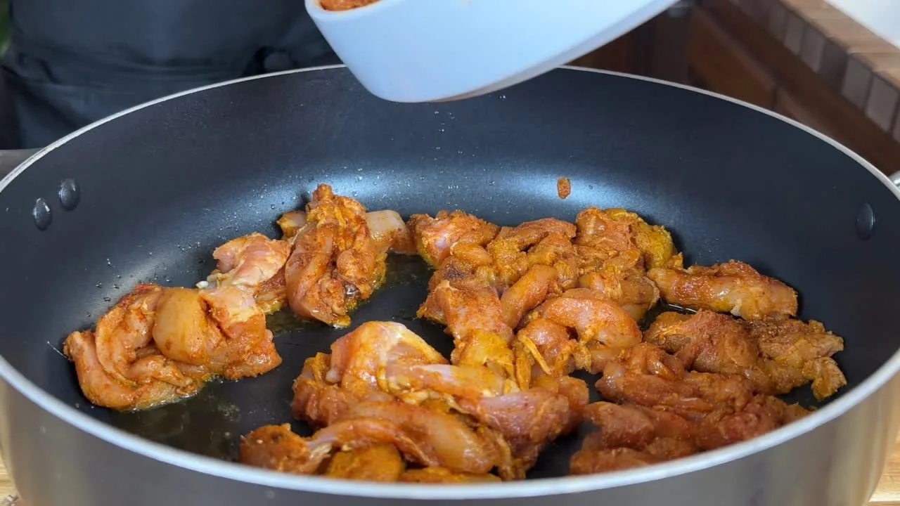 Cooking marinated chicken in a skillet for a savory dish.