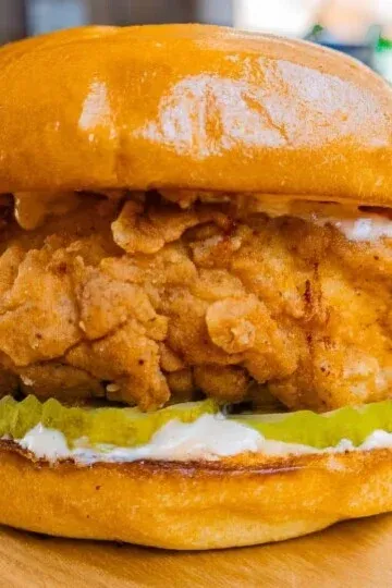 Crispy fried chicken sandwich with pickles on a golden bun, showcasing delicious savory flavors.