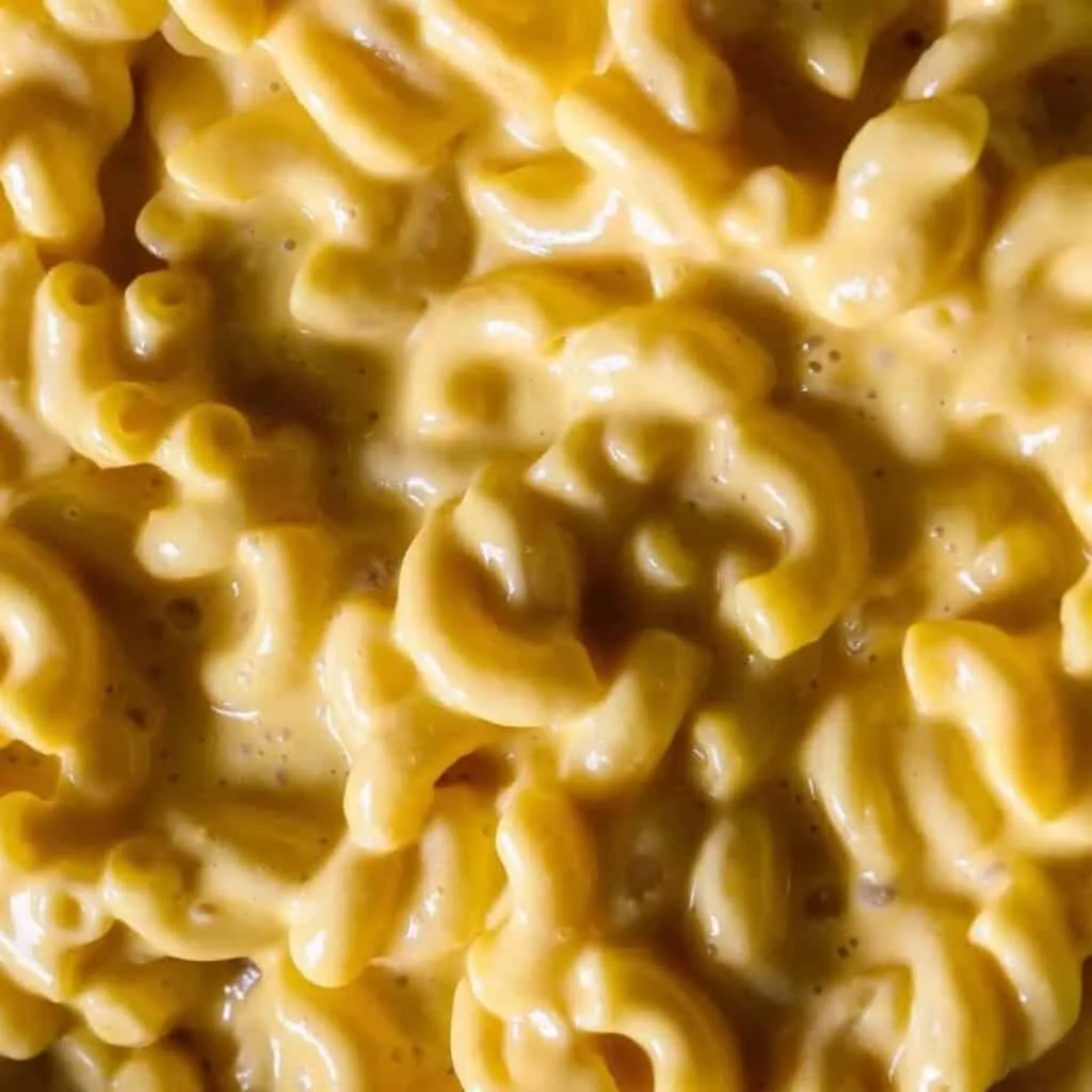 Creamy gouda mac and cheese close-up with rich, golden sauce coating elbow pasta. Perfect comfort food dish.