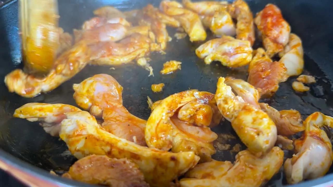 Chicken strips browning in a hot skillet, seasoned with spices, creating a delicious, savory dish.