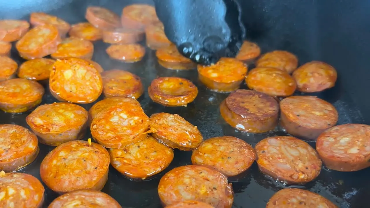 Slices of chorizo sausage sizzling in a hot pan, ready to serve.