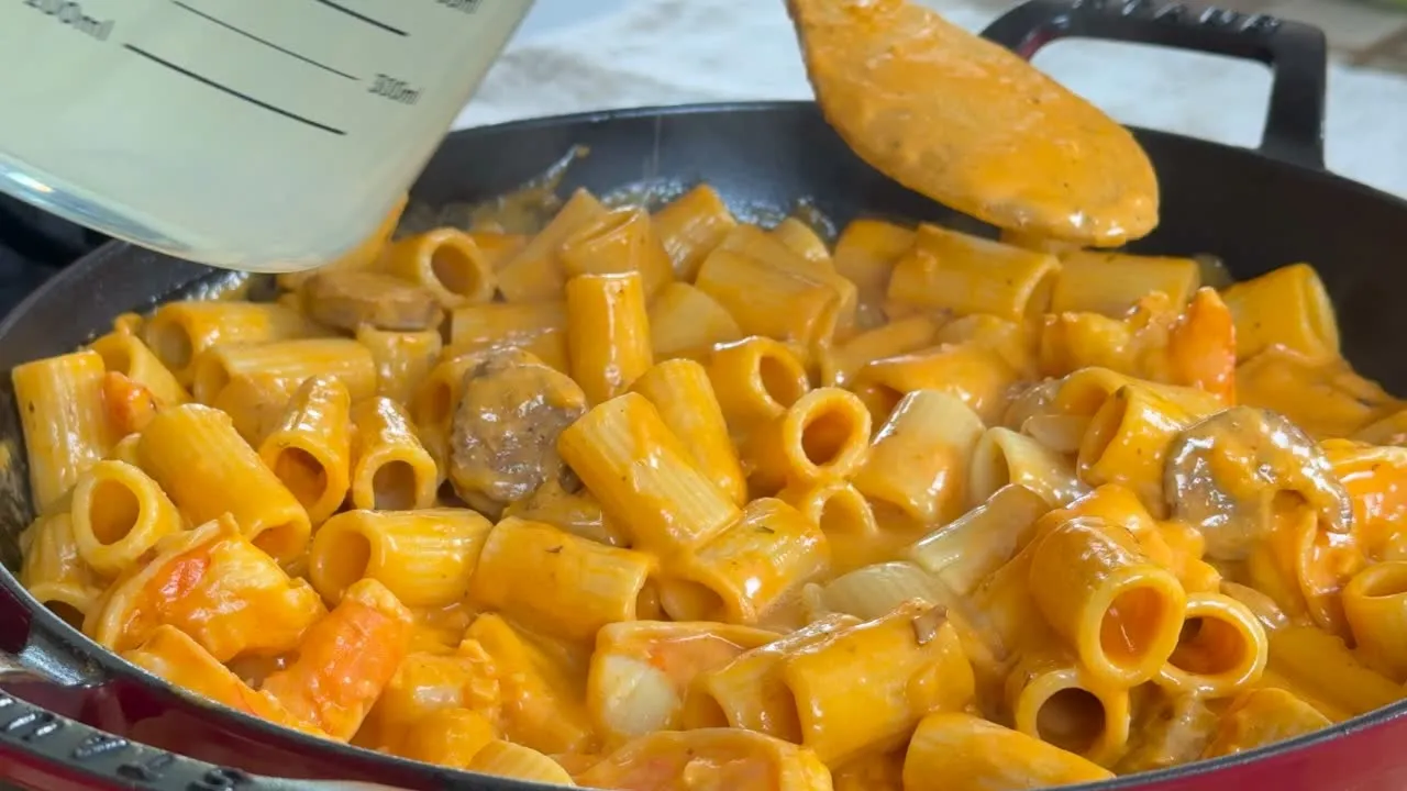 Creamy rigatoni pasta with sausage and shrimp in a skillet.