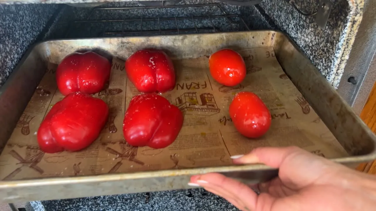 Roasting red bell peppers and tomatoes in oven on a baking tray.