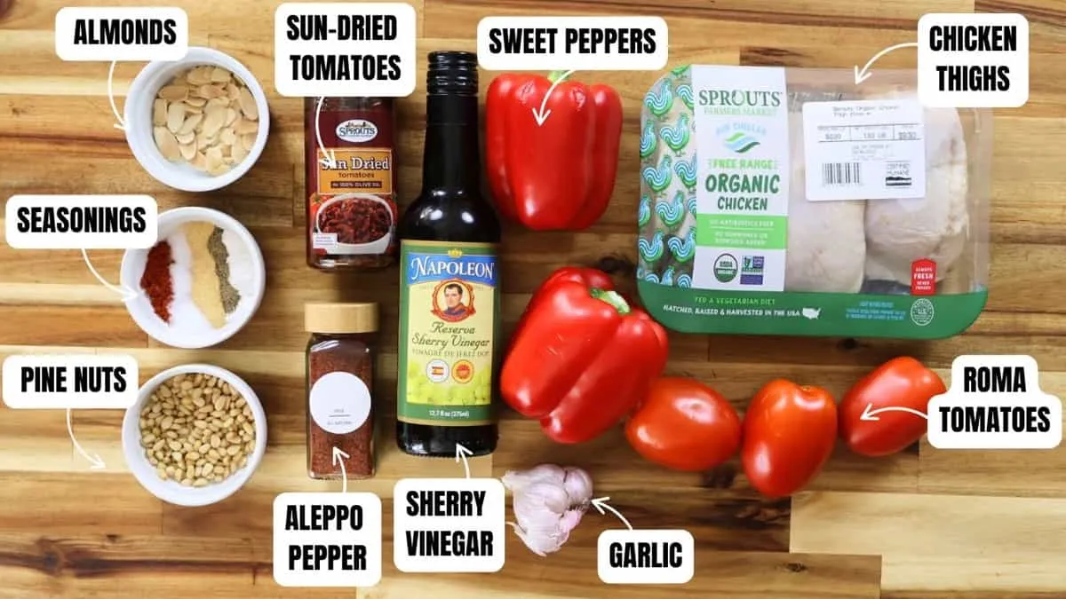 Ingredients for chicken romesco with pasta. Almonds, sun-dried tomatoes, seasonings, pine nuts, peppers, garlic, chicken thighs, and more.