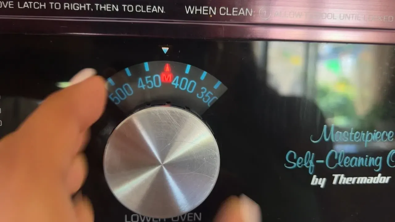 Hand adjusting a Thermador oven dial set to 425 degrees.