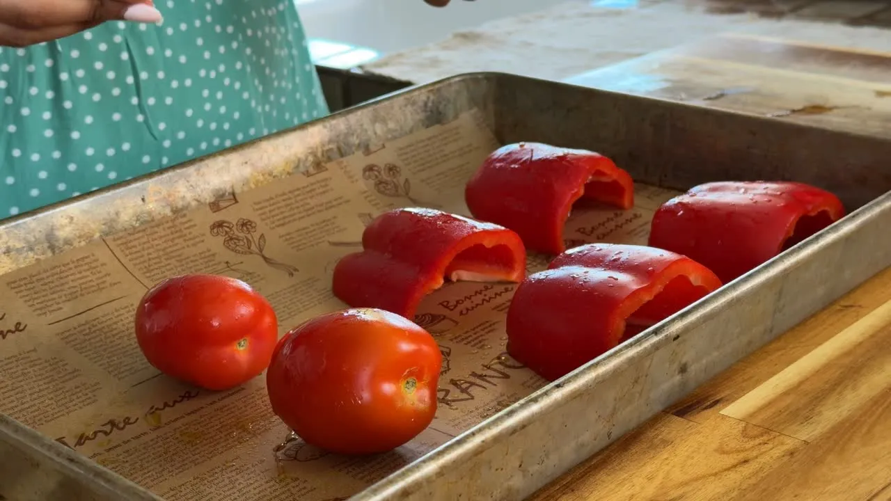 Fresh red peppers and tomatoes on a baking tray ready for cooking.