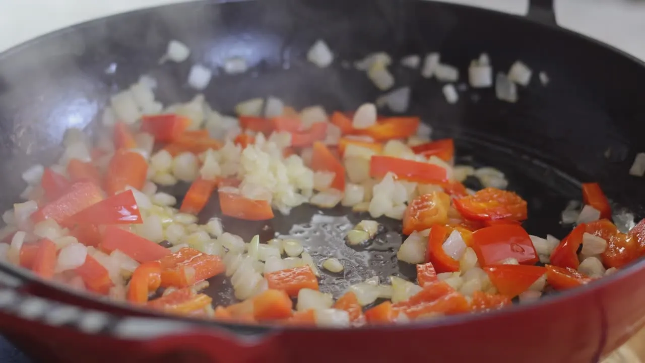 Sizzling red bell peppers and onions in a skillet.