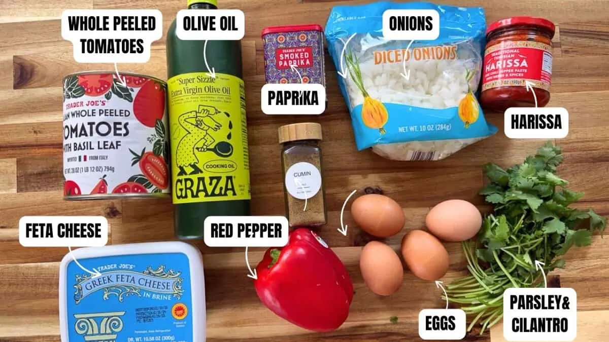 Ingredients for shakshuka: whole peeled tomatoes, olive oil, paprika, onions, harissa, feta cheese, red pepper, eggs, herbs.