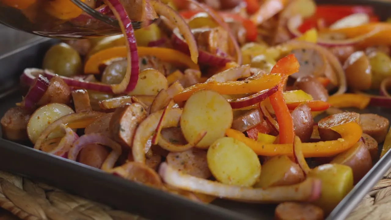 Roasted vegetables and sausage medley with bell peppers and onions on a baking sheet.