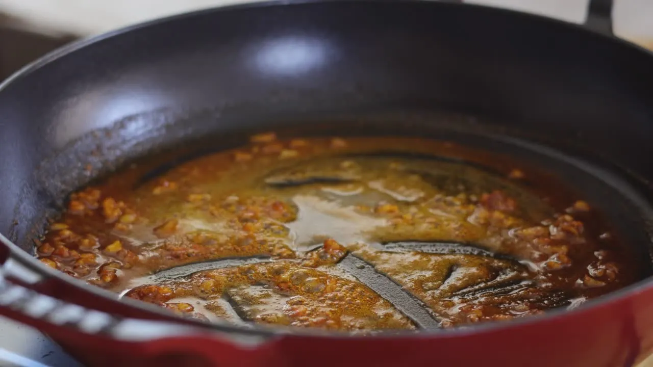 Sizzling spices in a red pan.