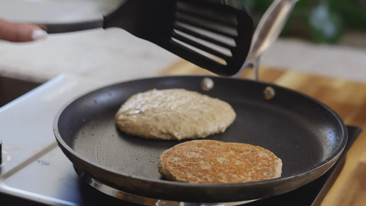 Cooking pancakes on a non-stick pan with a spatula.