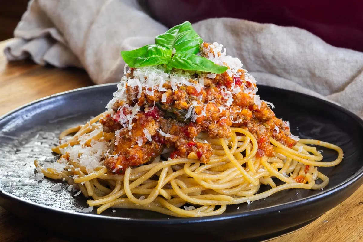 Spaghetti with rich hidden veggie pasta sauce topped with fresh basil and grated cheese on a black plate.
