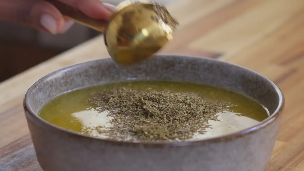 Making a herby dressing in a bowl on a wooden countertop.