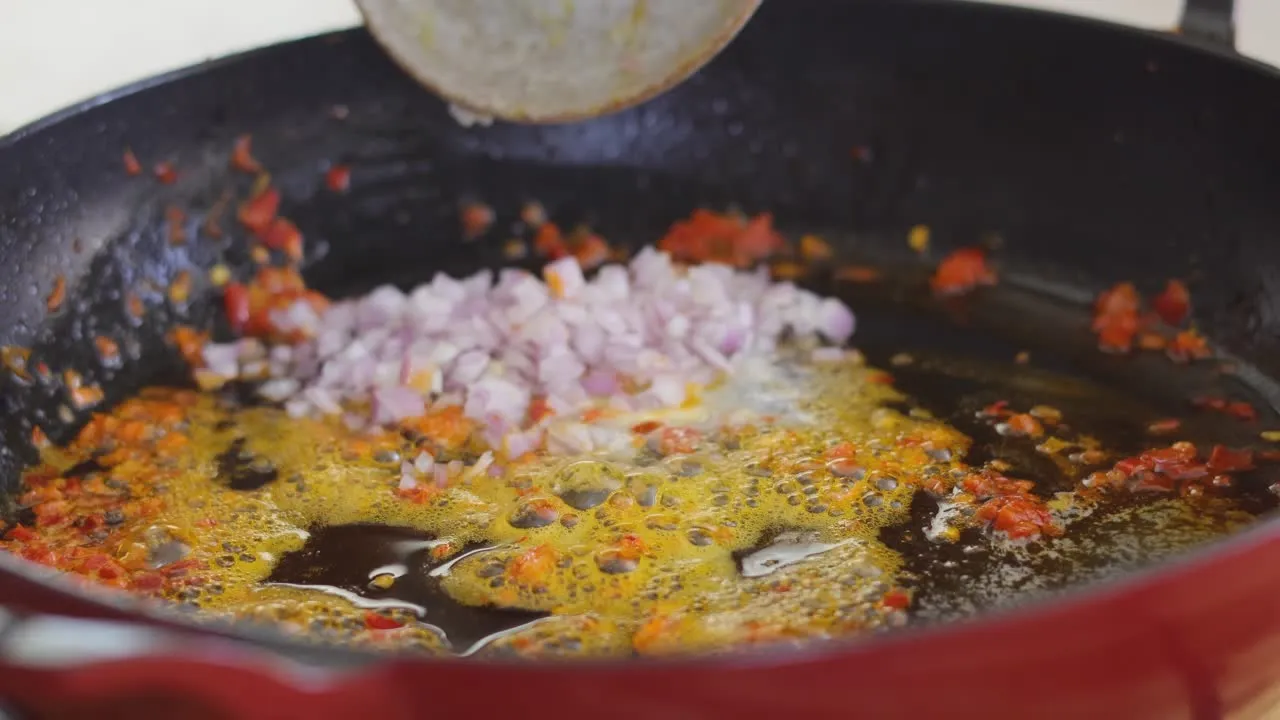 Chopped onions and peppers sizzling in hot oil in a pan.