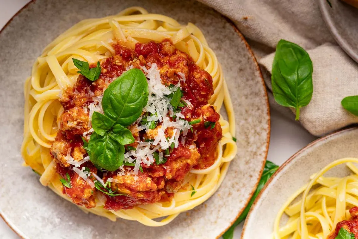 Hidden veggie pasta meat sauce, garnished with fresh basil and grated cheese on a plate.