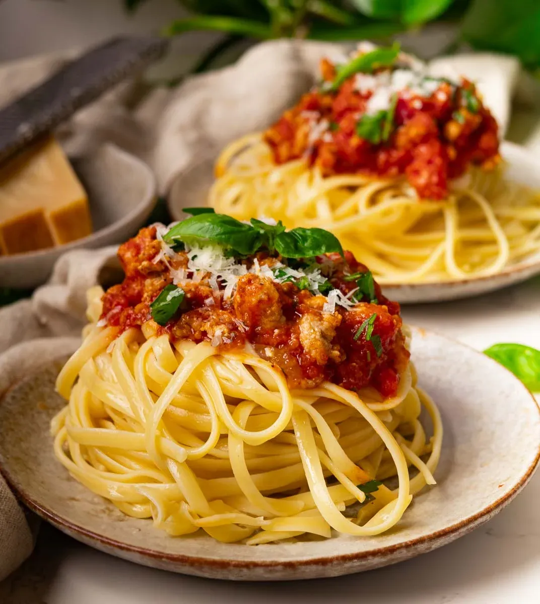 Plate of hidden veggie pasta meat sauce, garnished with basil and grated cheese.