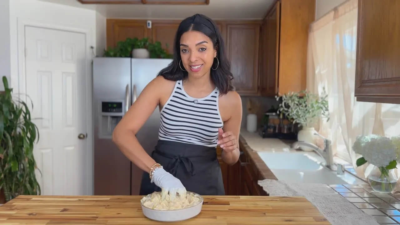Woman in striped top preparing a dish in a cozy kitchen.