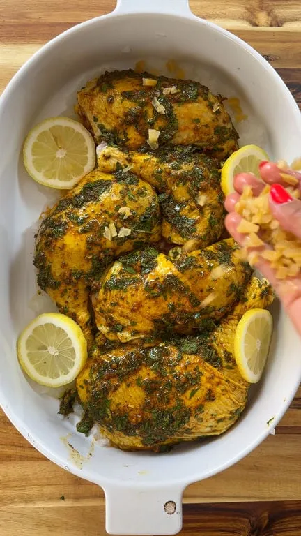 Herb-seasoned chicken in a dish, garnished with lemon slices.
