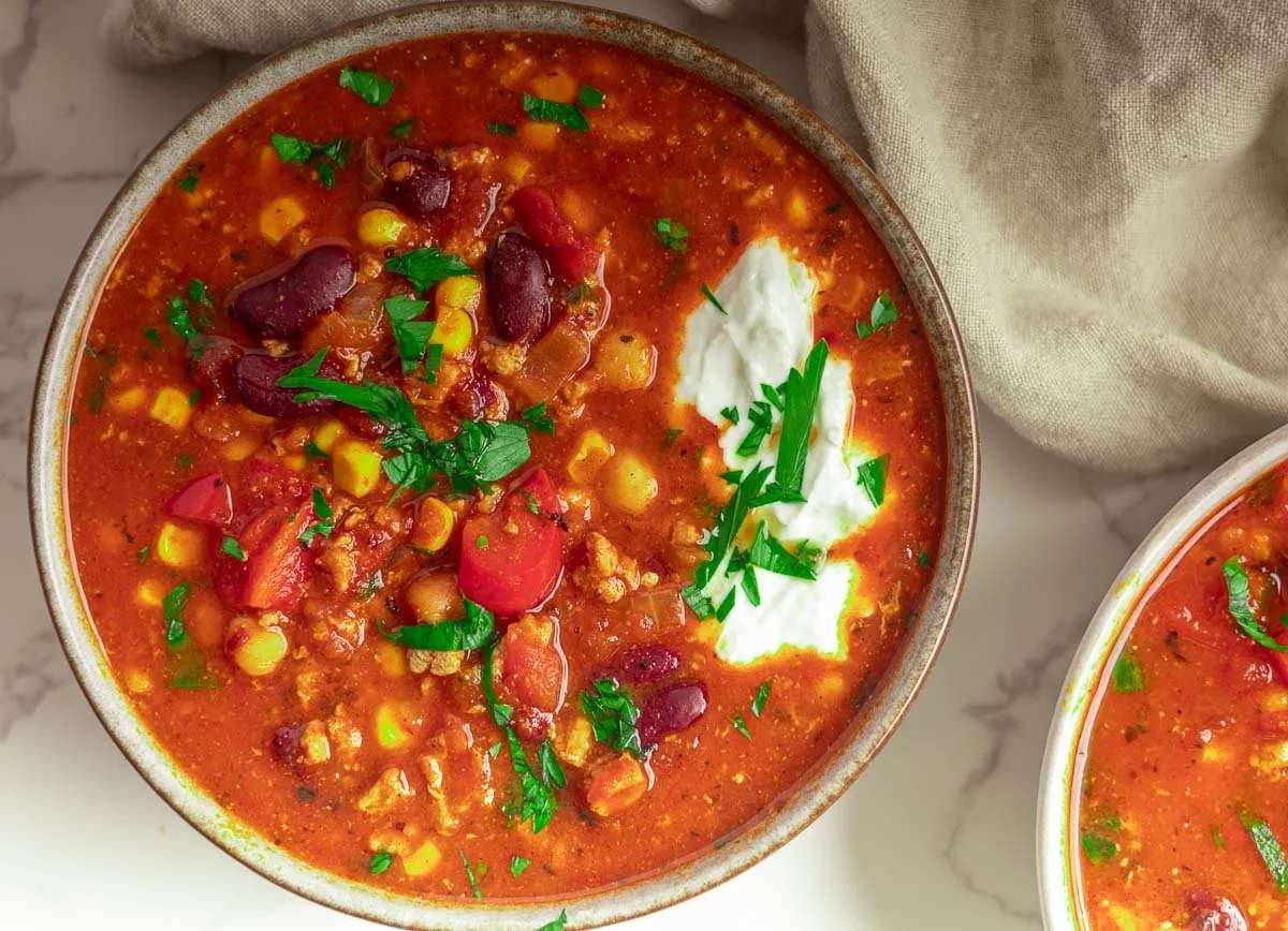 A bowl of hearty Mediterranean Bean Stew with fresh herbs in a bowl on a marble surface.