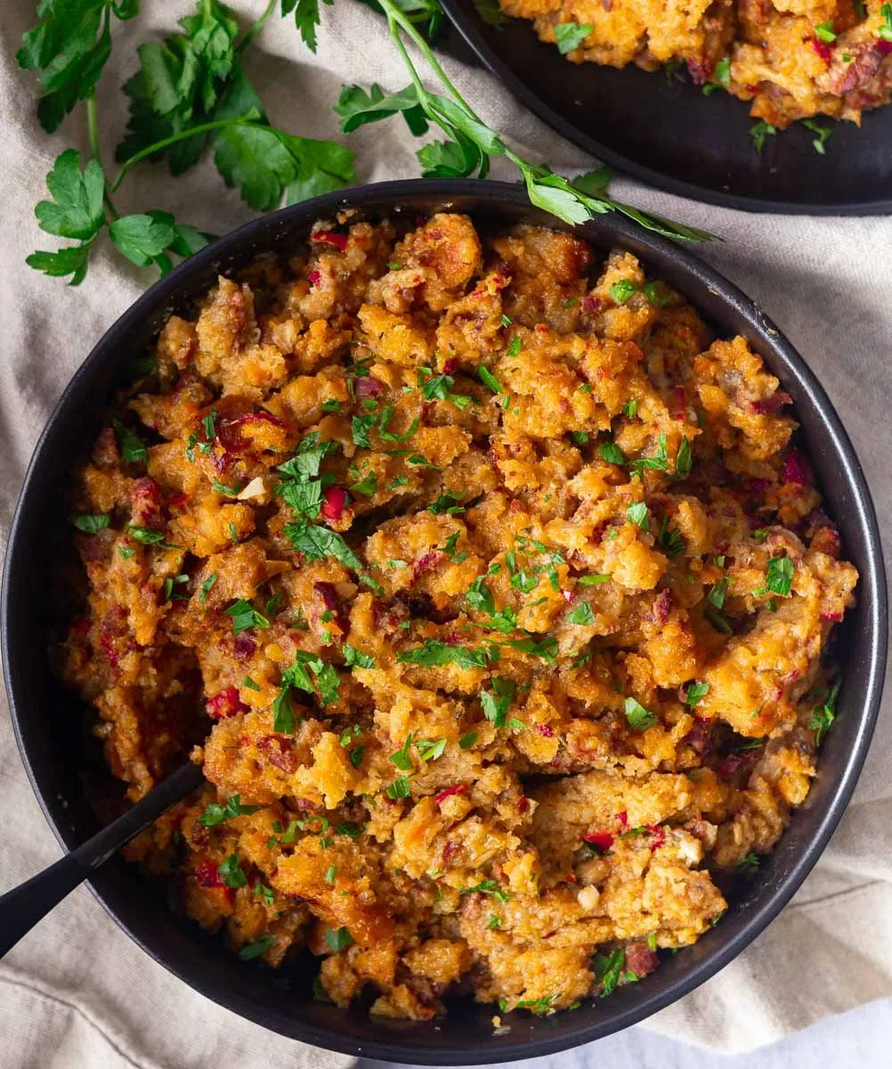 Chicken chorizo and stuffing casserole garnished with fresh parsley in a black bowl.