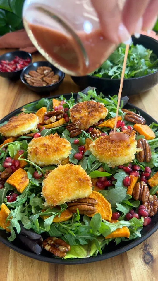 Salad with fried goat cheese, arugula, pecans, sweet potatoes, pomegranate seeds, drizzled with dressing.