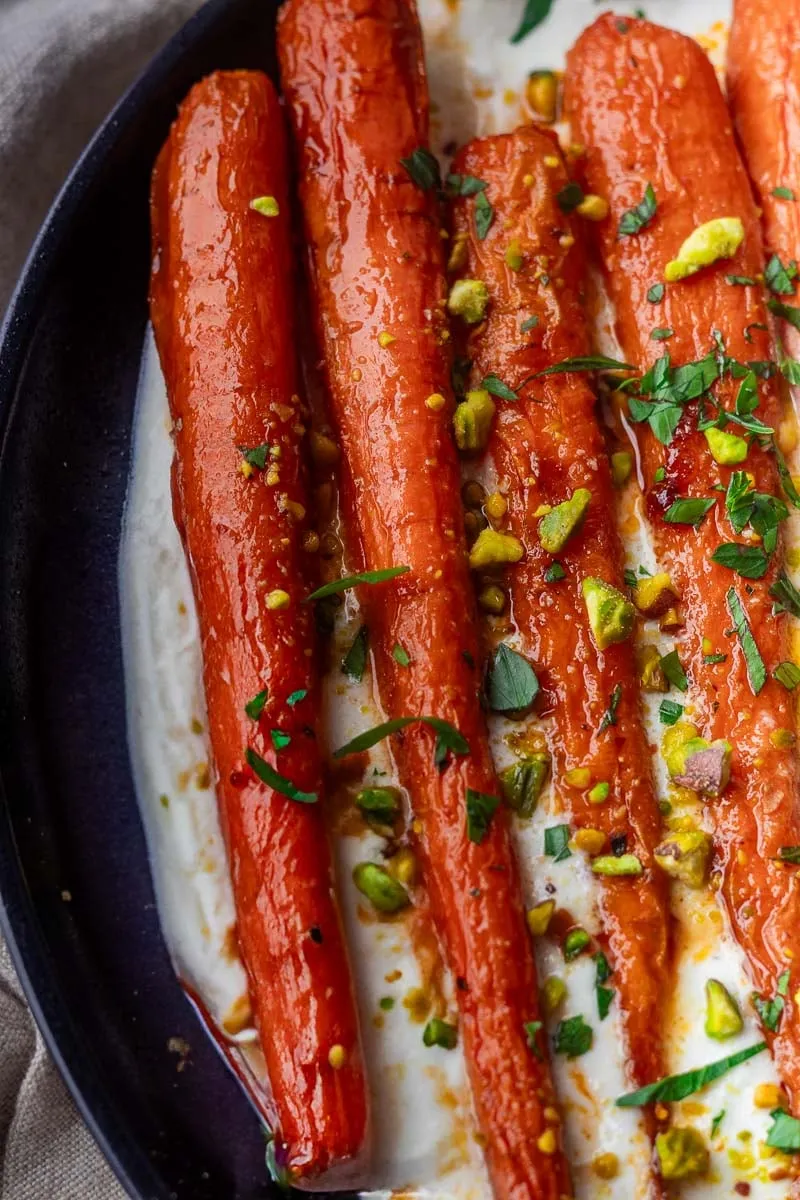 Roasted Harissa Maple Carrots with pistachio and herbs on creamy yogurt sauce.