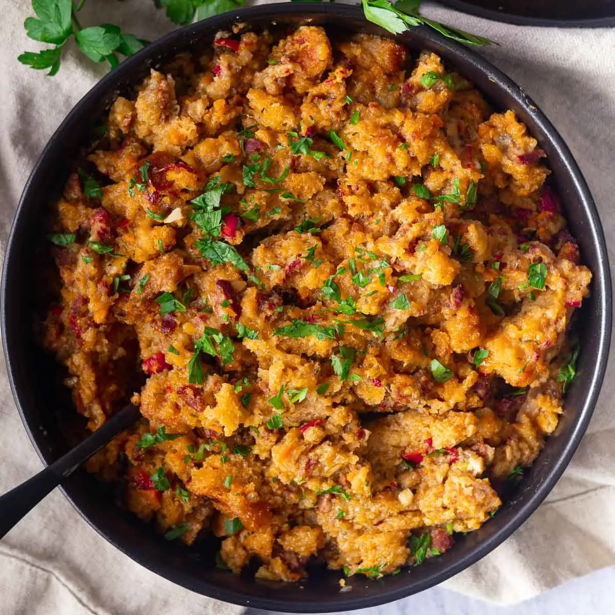 Bowl of savory Chicken chorizo and stuffing casserole with herbs and cranberries.