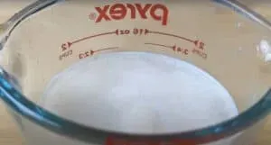 Pyrex measuring cup filled with ingredients, displaying measurement markings.