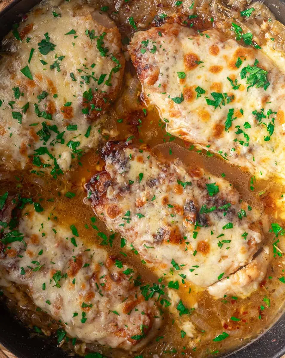 French onion soup chicken garnished with parsley in a pan.