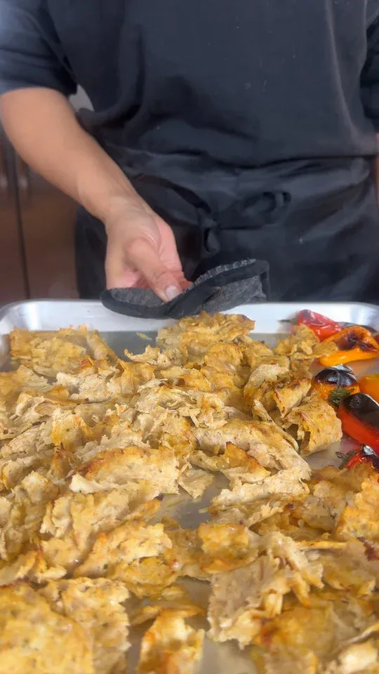 Person holding tray of cooked shredded chicken and roasted peppers.