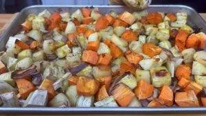 Roasted sweet potatoes and eggplants on a baking sheet, seasoned and cooked to perfection.