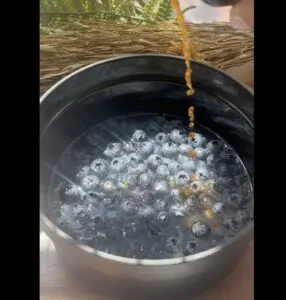 Fresh blueberries in a pot with honey drizzle, sunlight shining on rustic wooden table. Perfect for healthy recipes.