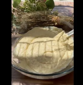 Creamy cake batter in a glass bowl, with sunlight casting shadows, ready for baking.