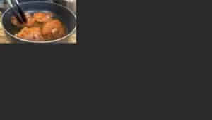 Cooking spicy marinated chicken in a pan with tongs, sizzling in hot oil. Perfect for a flavorful meal.