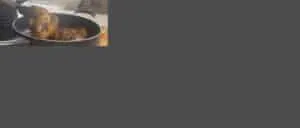 Person frying seasoned chicken thighs in a nonstick pan, showcasing the cooking process in a kitchen setting.