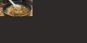 Stirring fragrant spiced rice in a pot with a wooden spoon, showcasing a delicious cooking process.