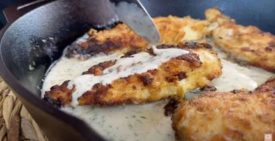 Golden fried chicken in a creamy dill sauce in a skillet. Delicious home-cooked meal.