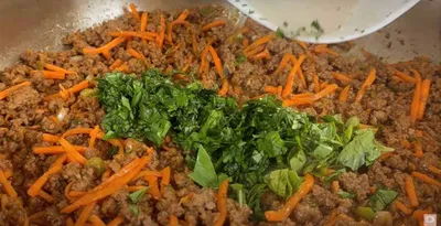 Ground beef with carrots and fresh herbs in a pan, perfect for tasty homemade tacos or a flavorful dinner base.