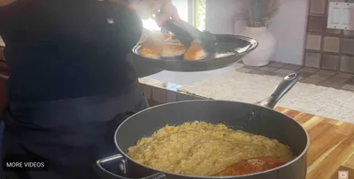 Chef plating grilled salmon over creamy orzo in a kitchen setting.
