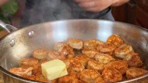 Sizzling shrimp with butter in a pan, perfect for a flavorful seafood dish.