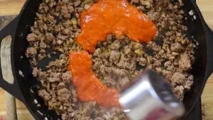 Cooking ground beef with tomato sauce in a skillet for a delicious meal preparation.