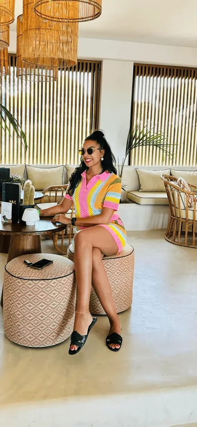 Woman in colorful outfit relaxing at a stylish cafe with modern decor and bamboo accents.