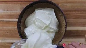 Mixing creamy cheesecake filling into a crumb crust in a springform pan on a wooden surface.