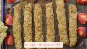 Baked chicken kebabs on a tray with tomatoes; internal temp should be 165F. Perfect for grilling or baking recipes.