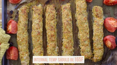 Baked chicken kebabs on a tray with tomatoes; internal temp should be 165F. Perfect for grilling or baking recipes.