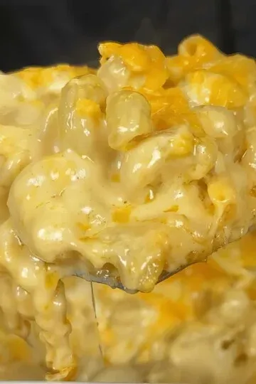 Creamy mac and cheese with gooey cheddar and pasta on a spoon, showing rich and cheesy texture.