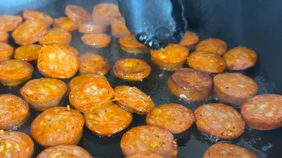 Slices of chorizo sausage sizzling in a hot pan, ready to serve.